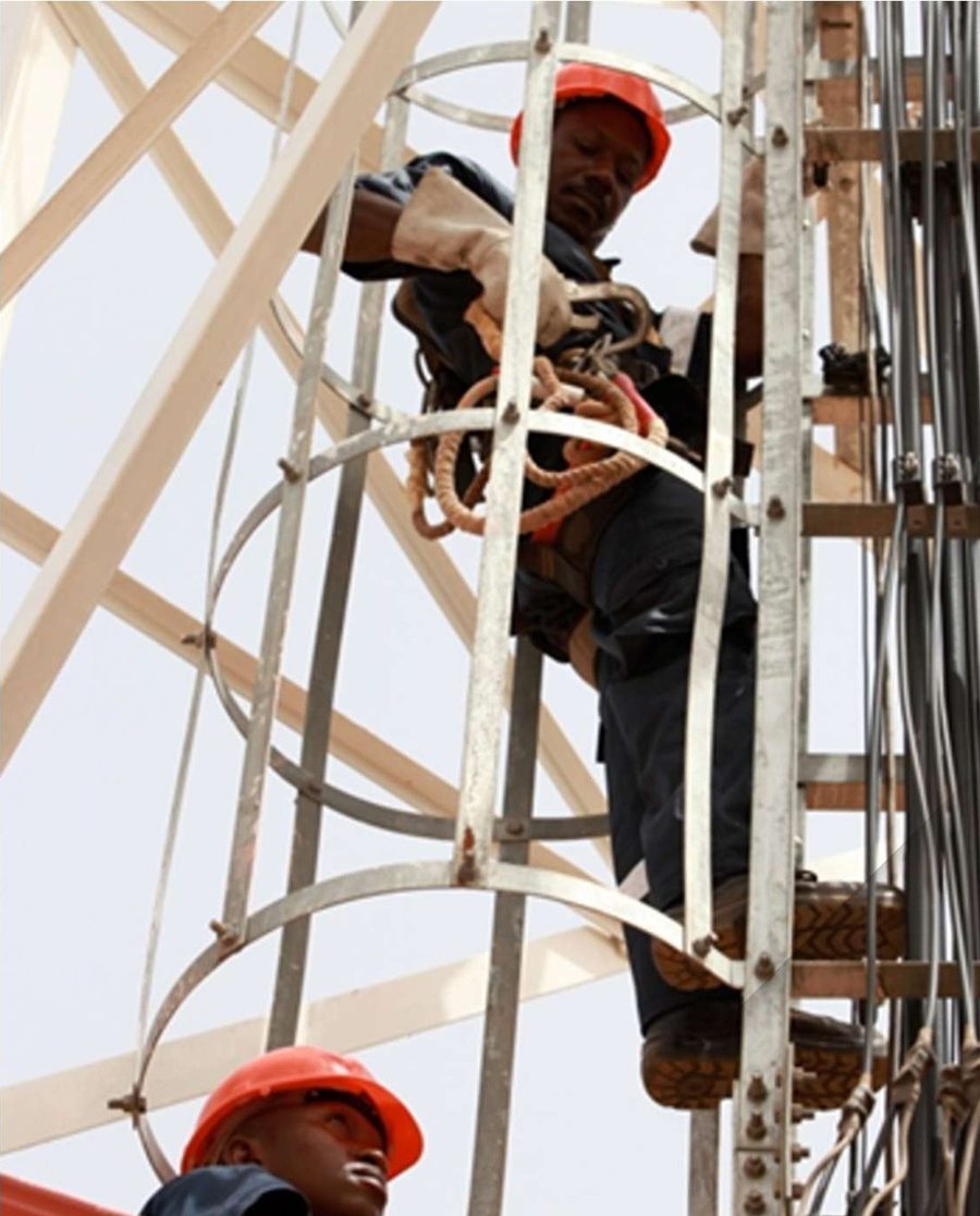 Deux techniciens FMAT-D travaillant en hauteur sur la structure d'un pylône